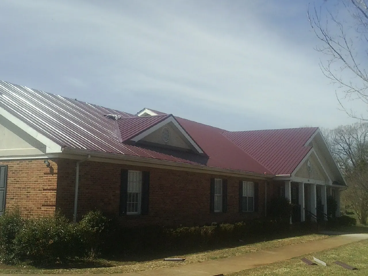 Red metal roof with gabled entries on a long brick building, from a Hail Damage Roof Repair job in Breckenridge