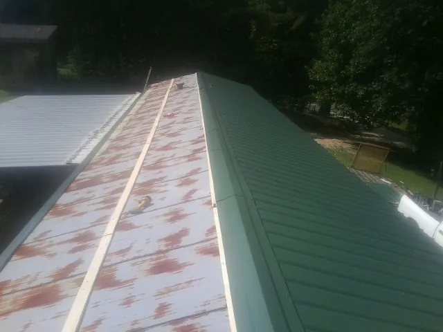Old rusted panels beside newly installed green metal roofing — Wind Damage Roof Repair by Roofing Brothers in Breckenridge