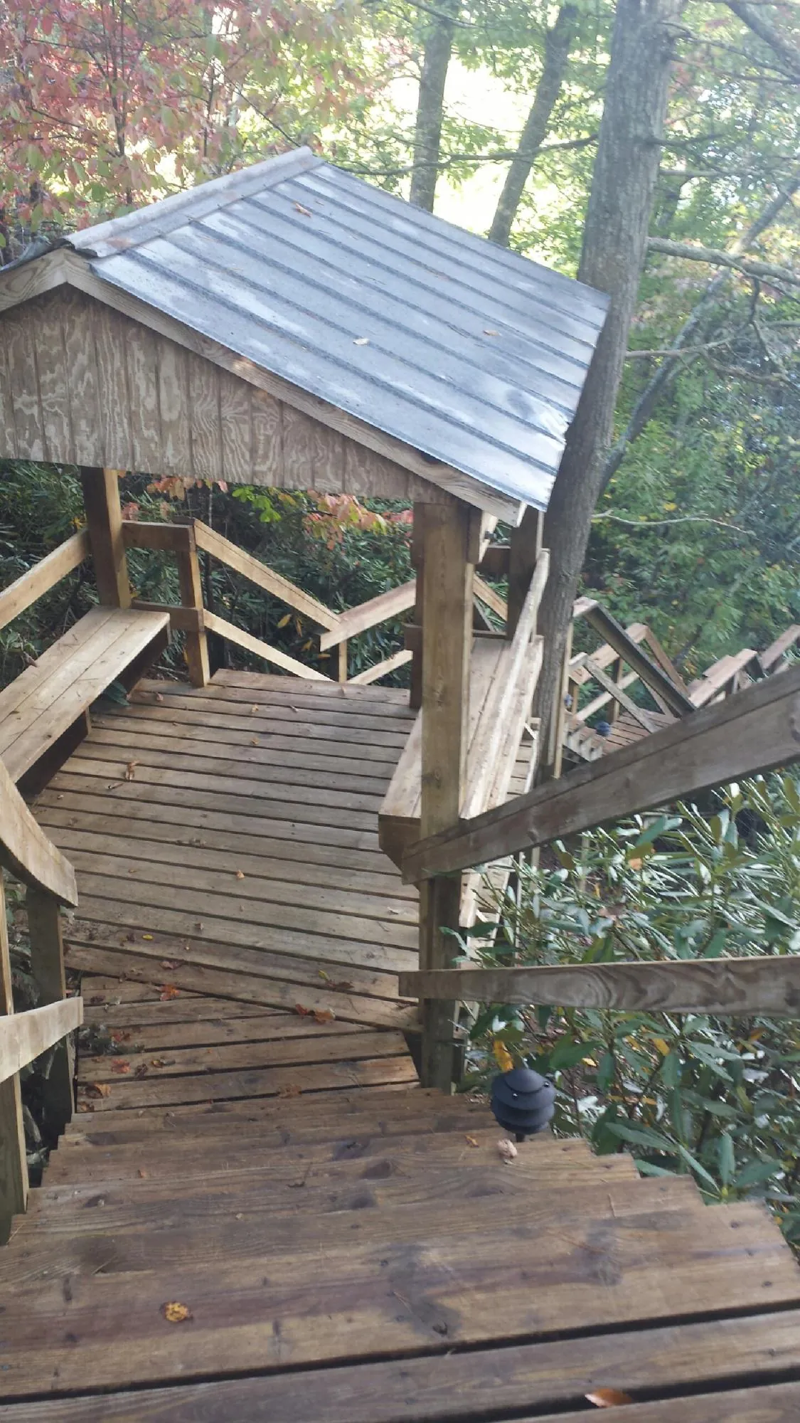 Metal roofed shelter over wooden steps on a wooded walkway — Skylight Repair & Installation work by our crew in Breckenridge