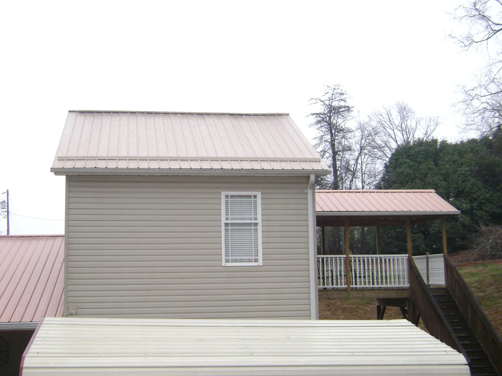 Tan metal roofs on a two story addition and attached porch, from a Roof Replacement job in Breckenridge