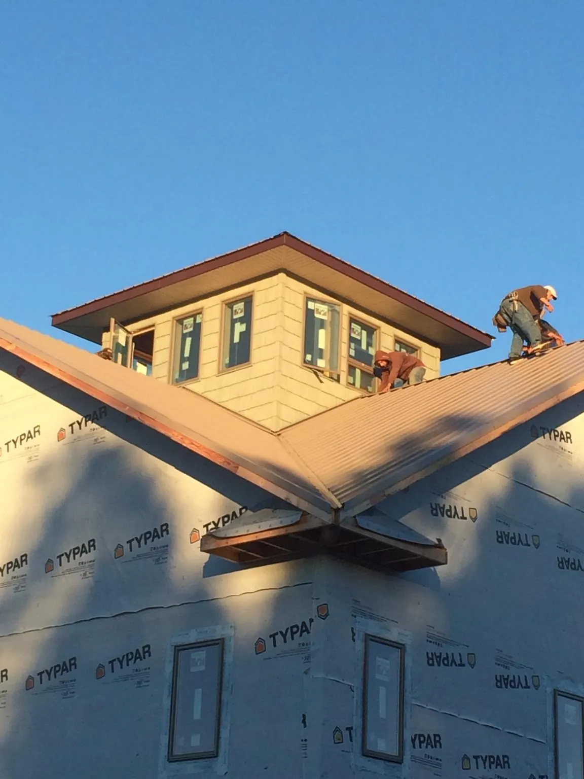 Roofers working around a rooftop cupola on a new metal roof at sunset — Roof Waterproofing in Breckenridge by Roofing Brothers
